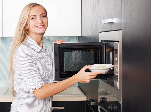  Mujer pone un plato en el microondas.